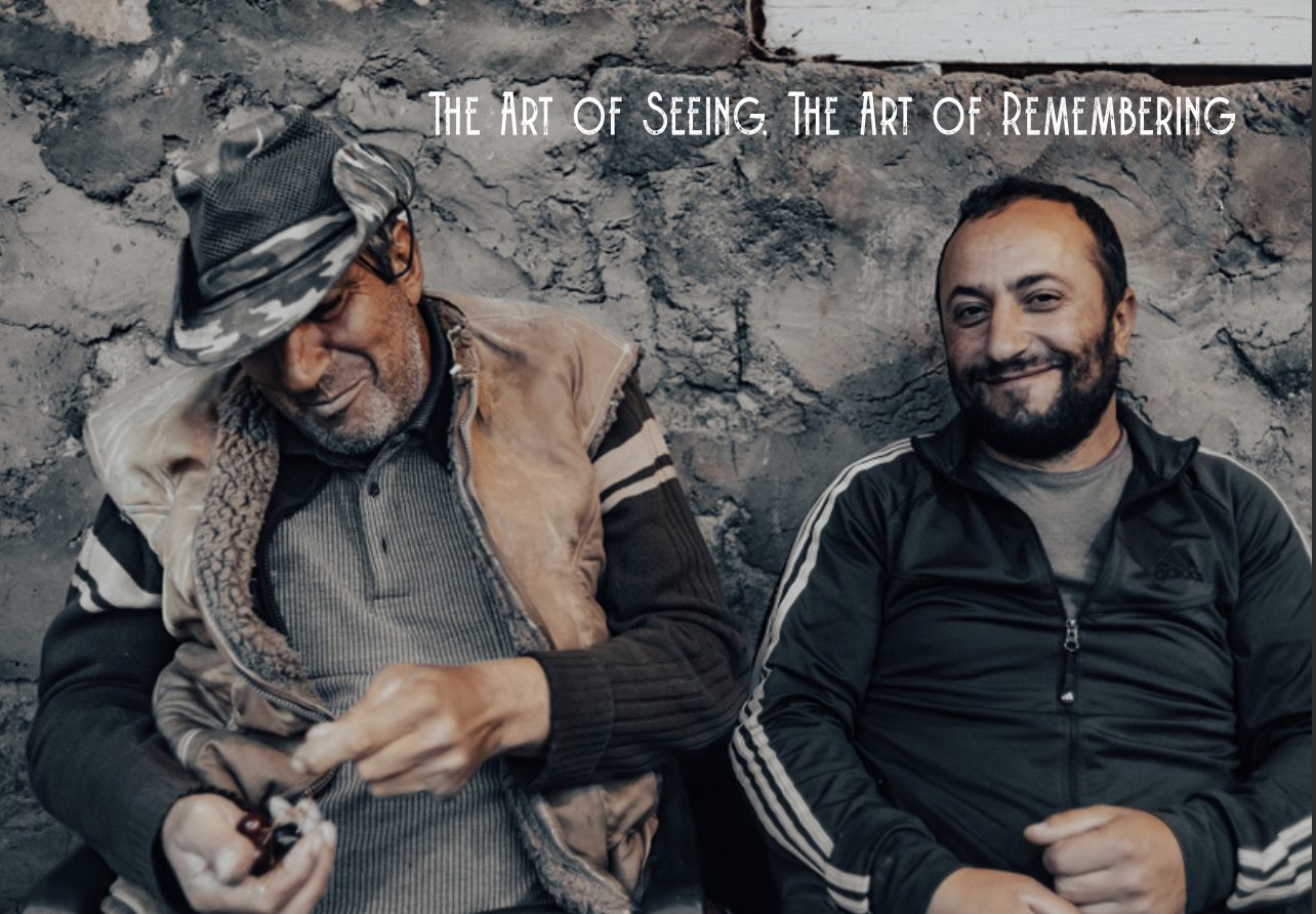 Cover of The Art of Seeing, The Art of Remembering: two men sit smiling against a weathered stone wall in Armenia