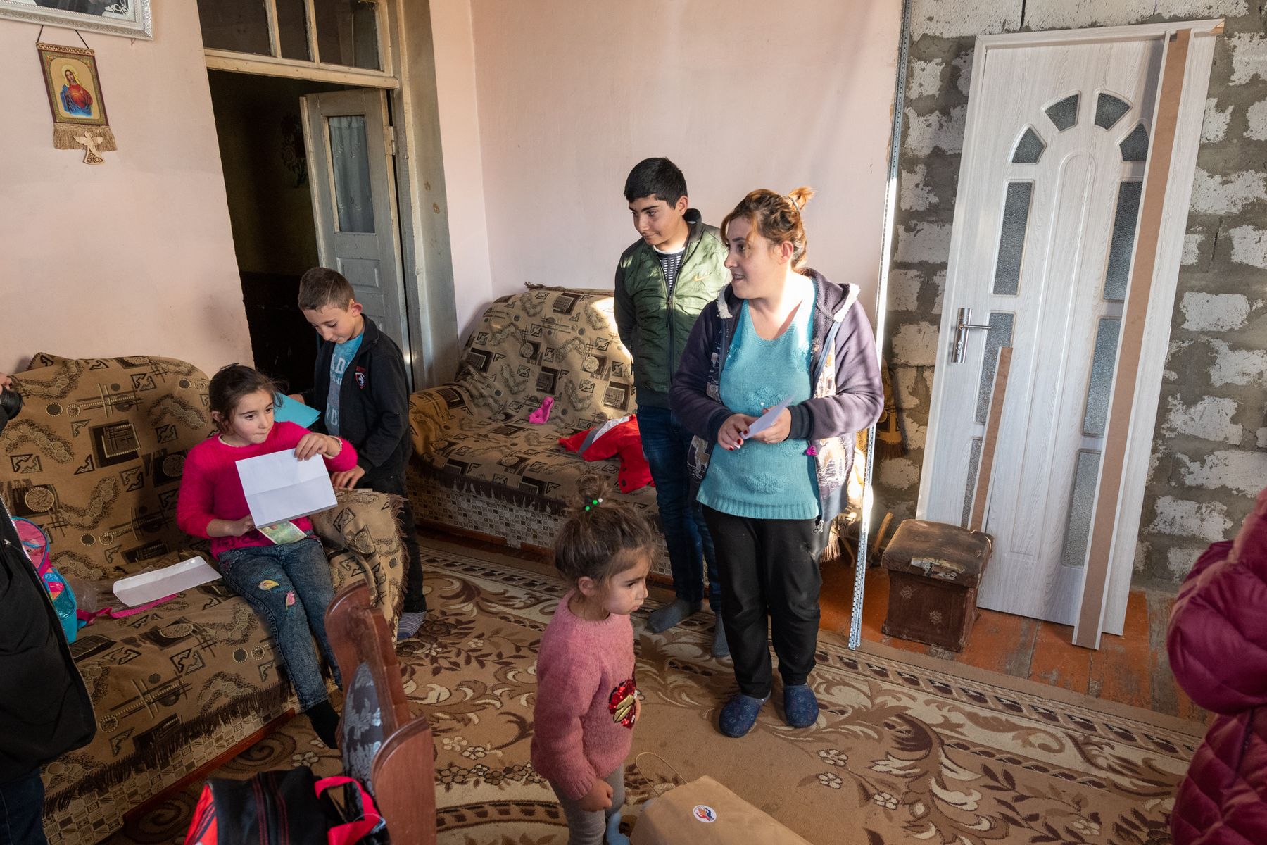 A family stands in a sitting room with children on the sofa