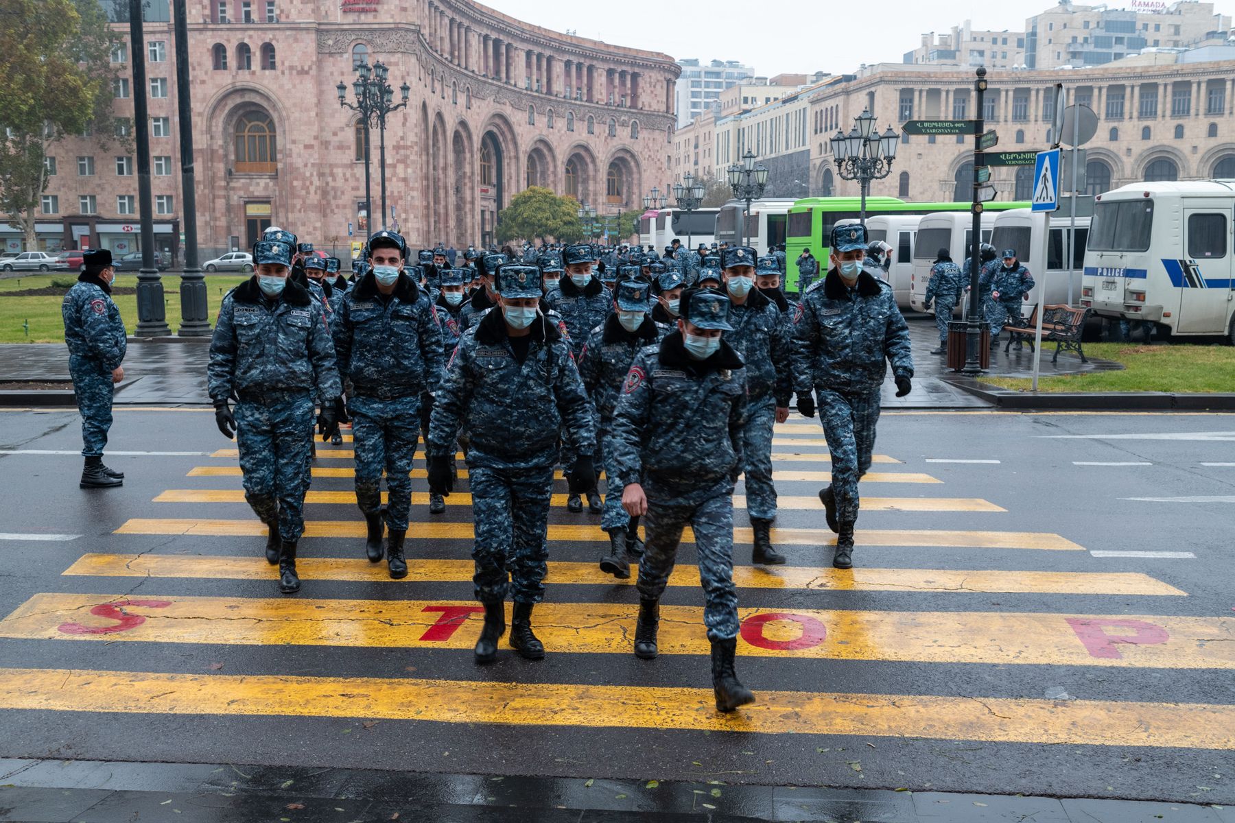 A column of riot police crosses a wet street in Yerevan