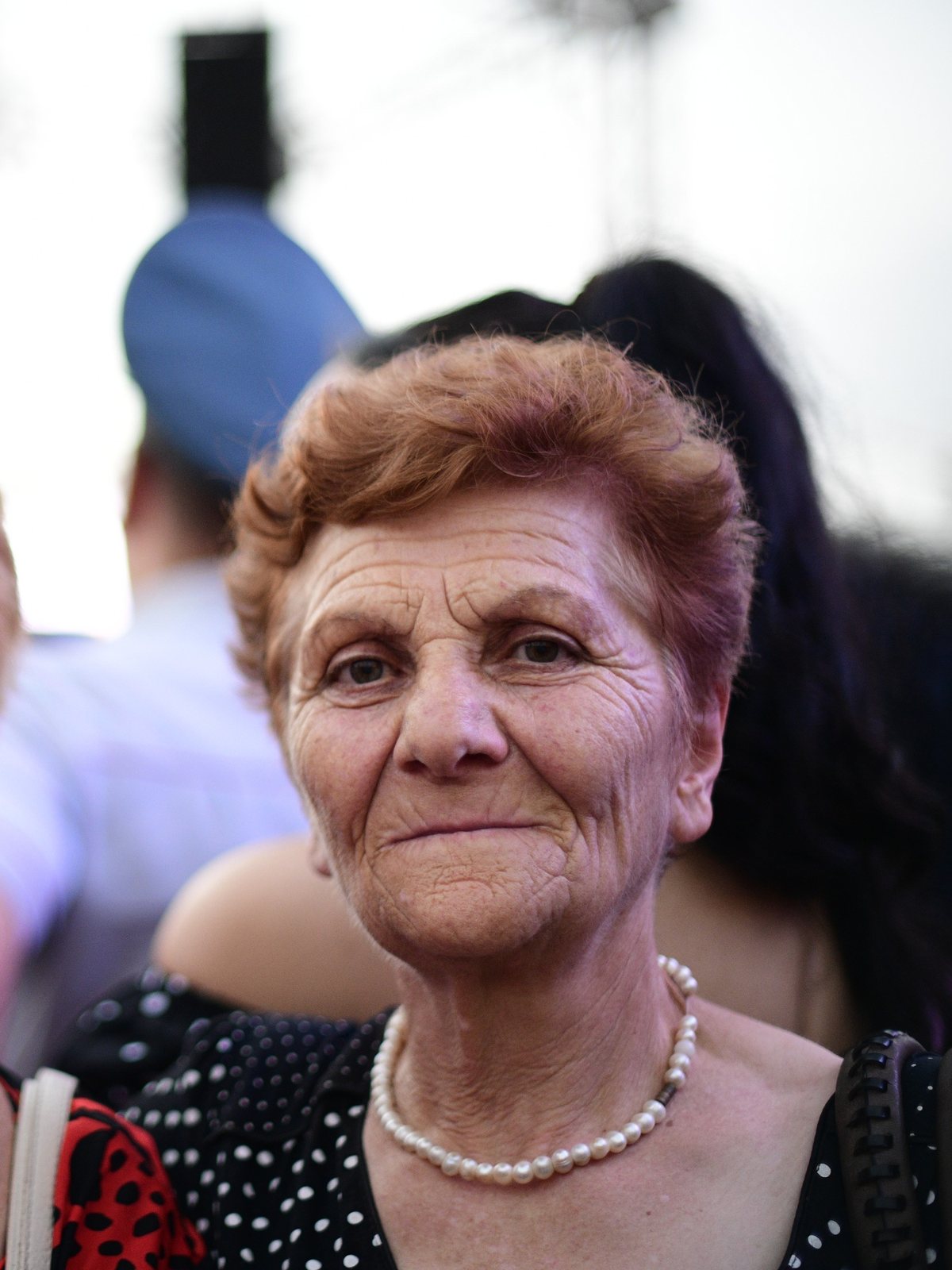An older woman in pearls looks into the camera, Yerevan