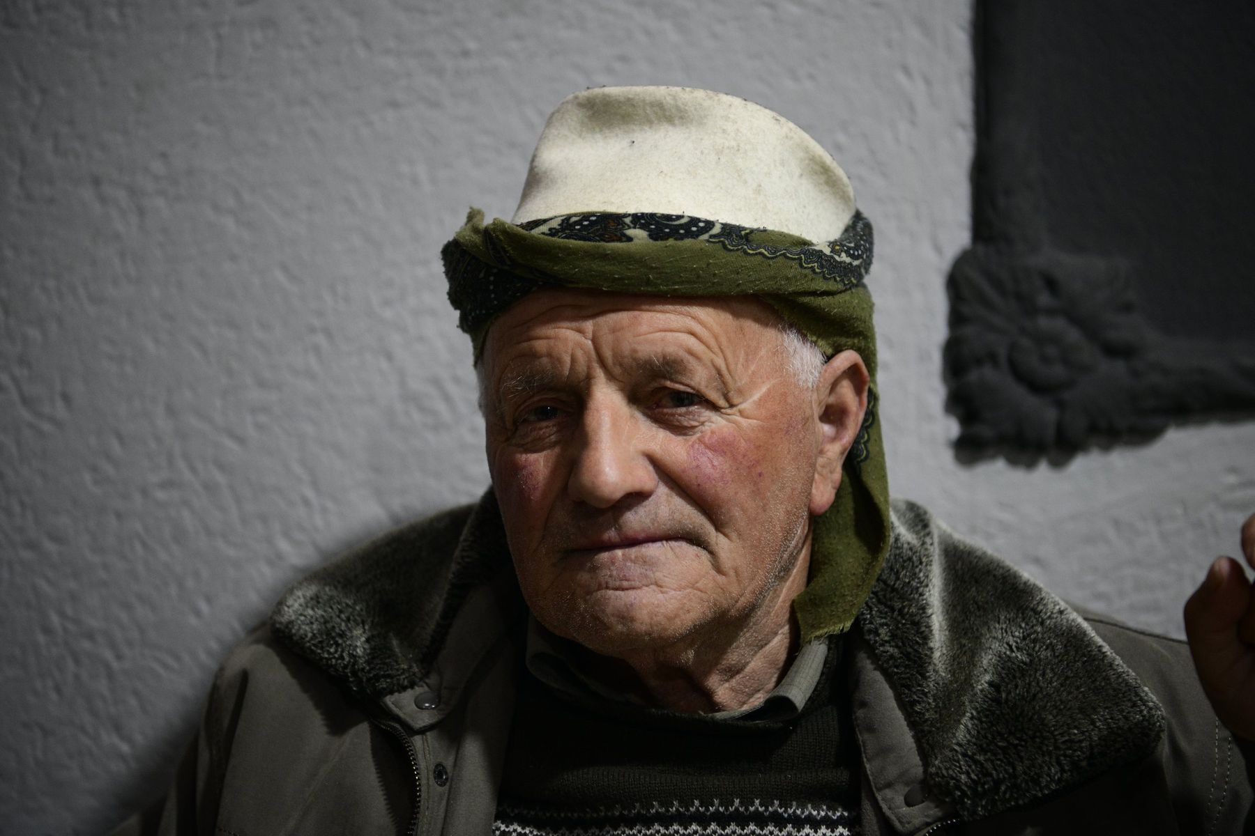 An elderly man in a white cap holds a walking stick, Kosovo