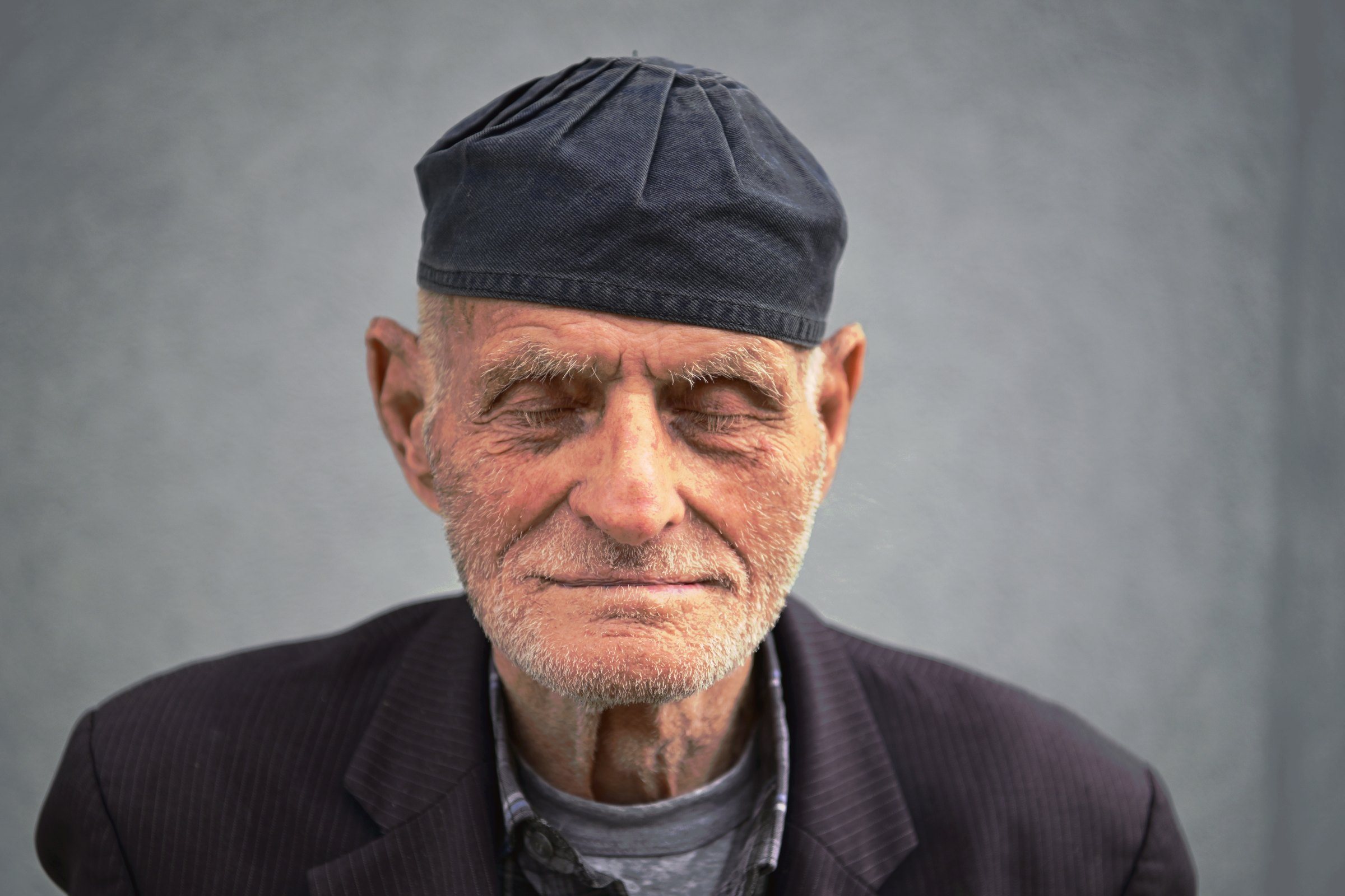 An elderly man in a dark cap, his eyes closed, eastern Kosovo