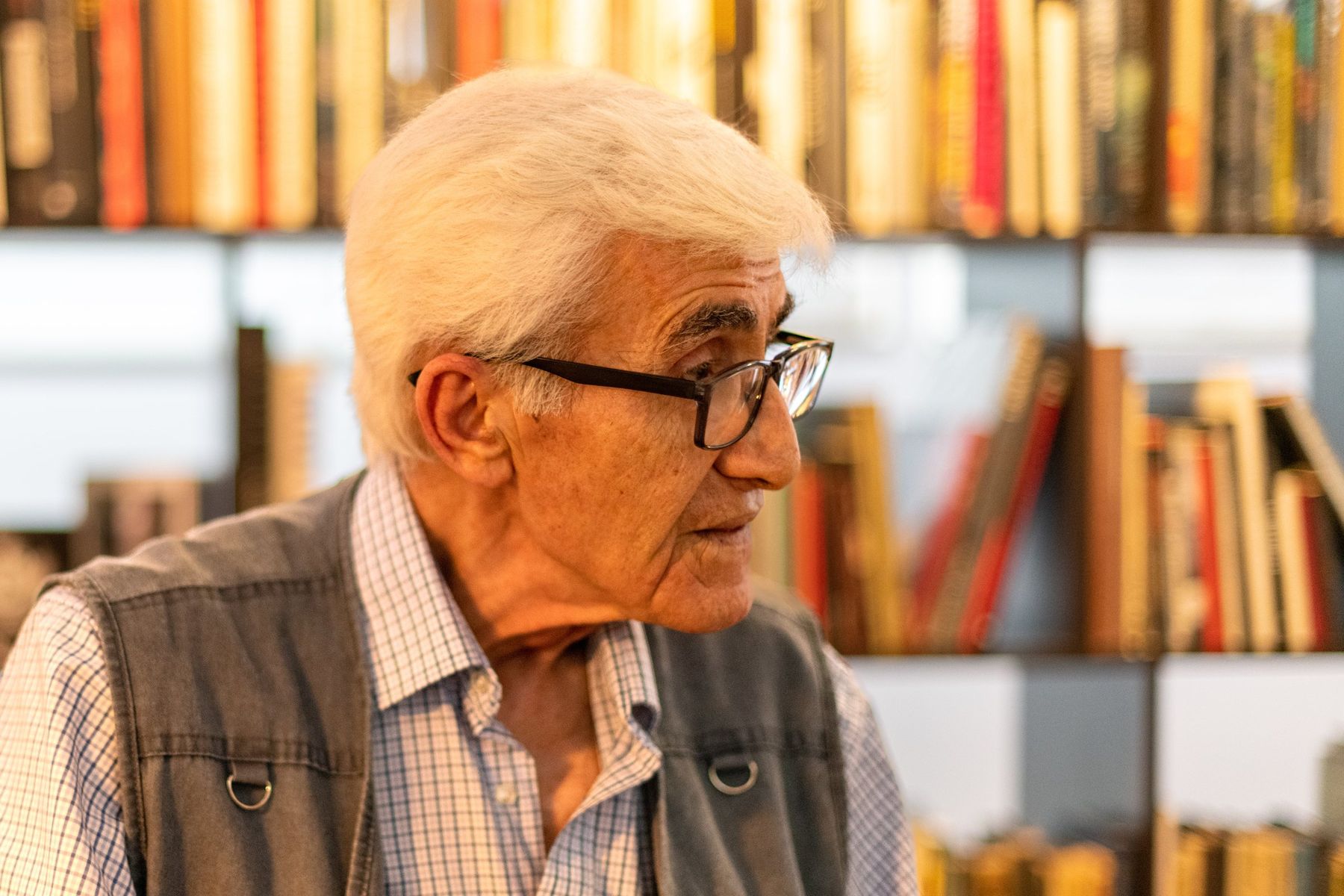 An elderly man in glasses among shelves of books