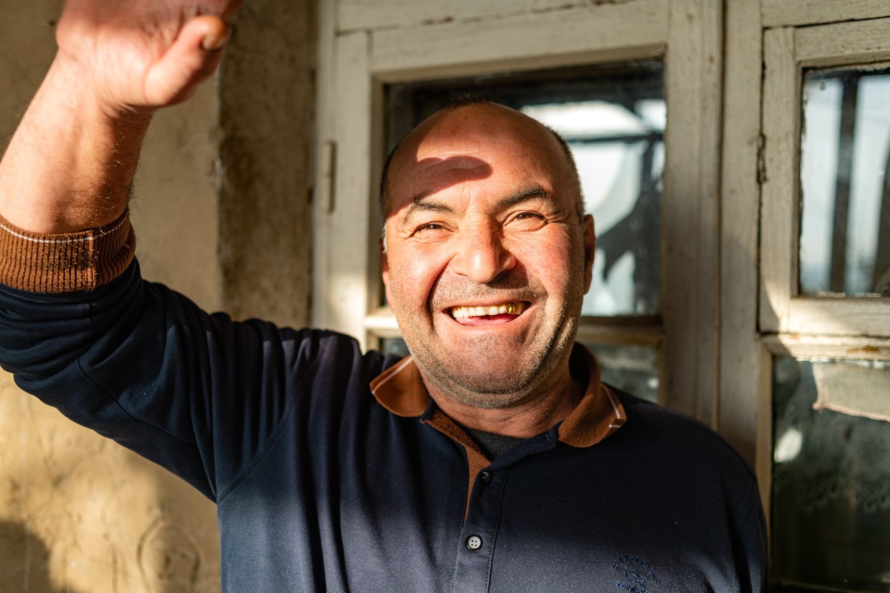 A man laughs and raises his arm in a doorway