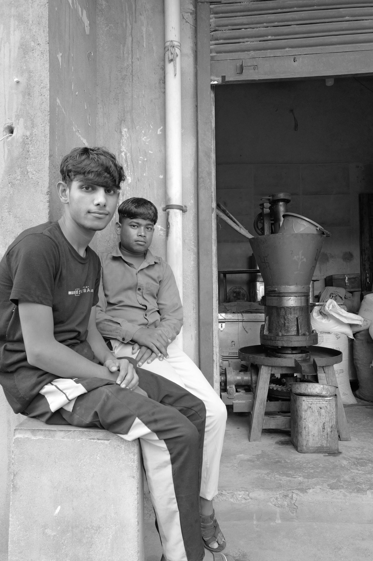 Two boys sit on a step outside a doorway