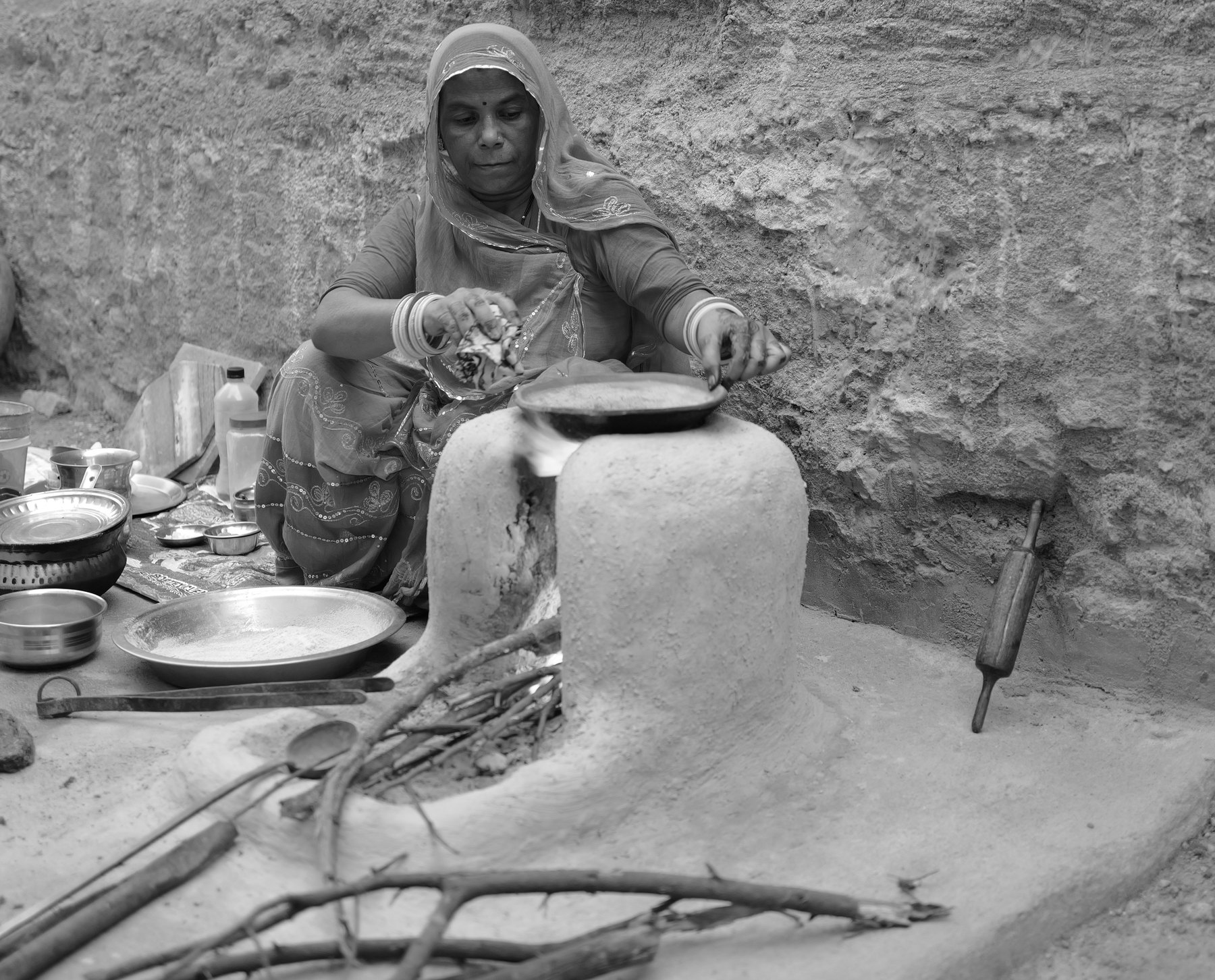 The woman cooks at the stove as the light fades