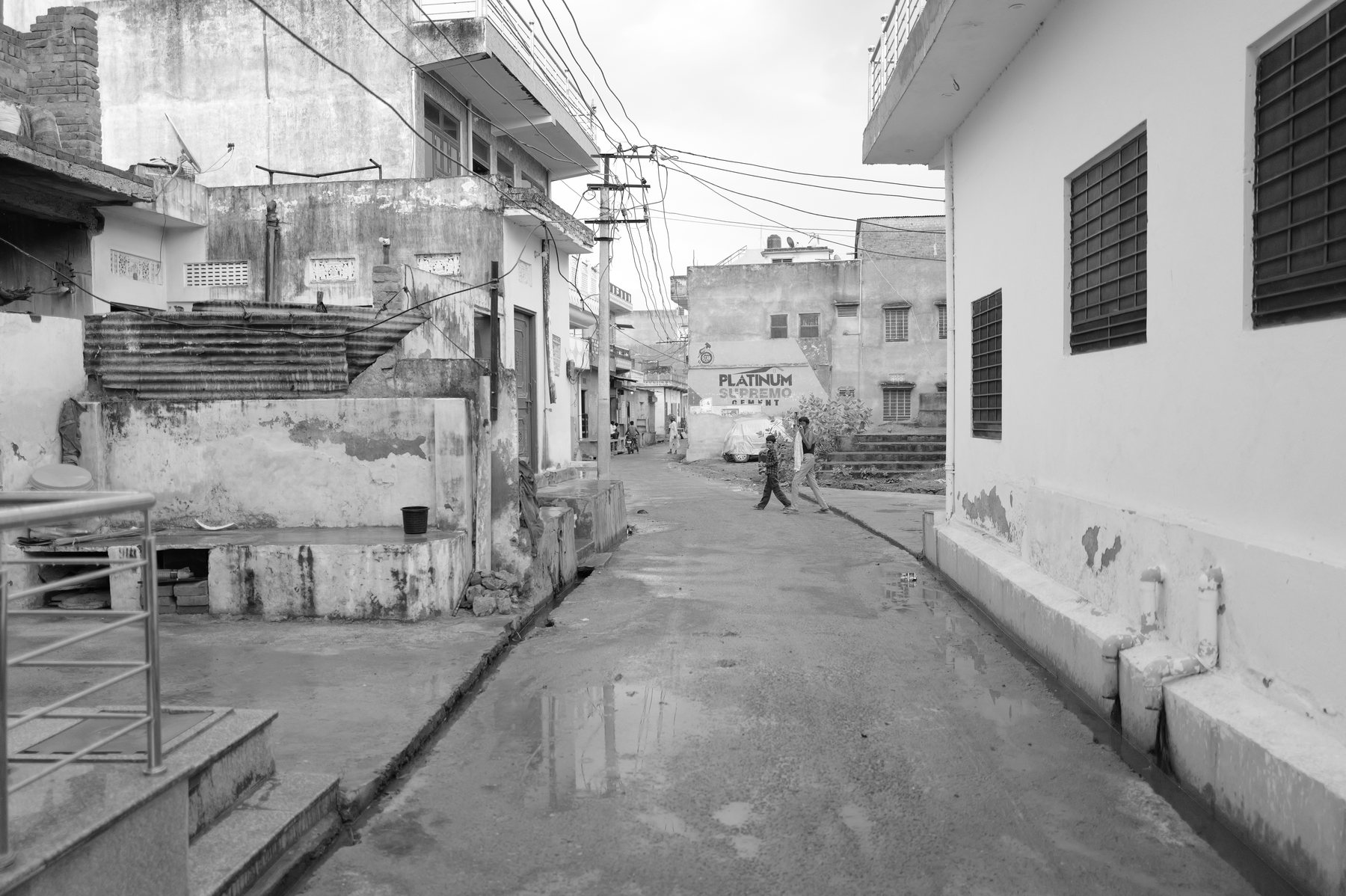 A wide village lane with whitewashed houses and overhead wires