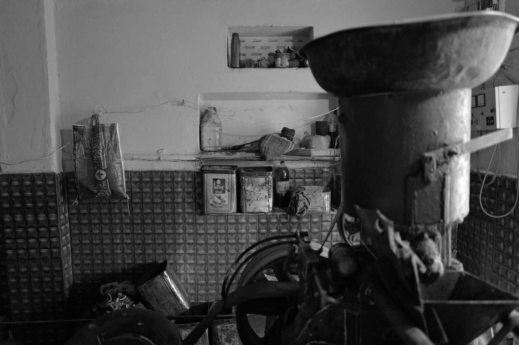 A flour grinding machine stands in a dim room beside a bicycle