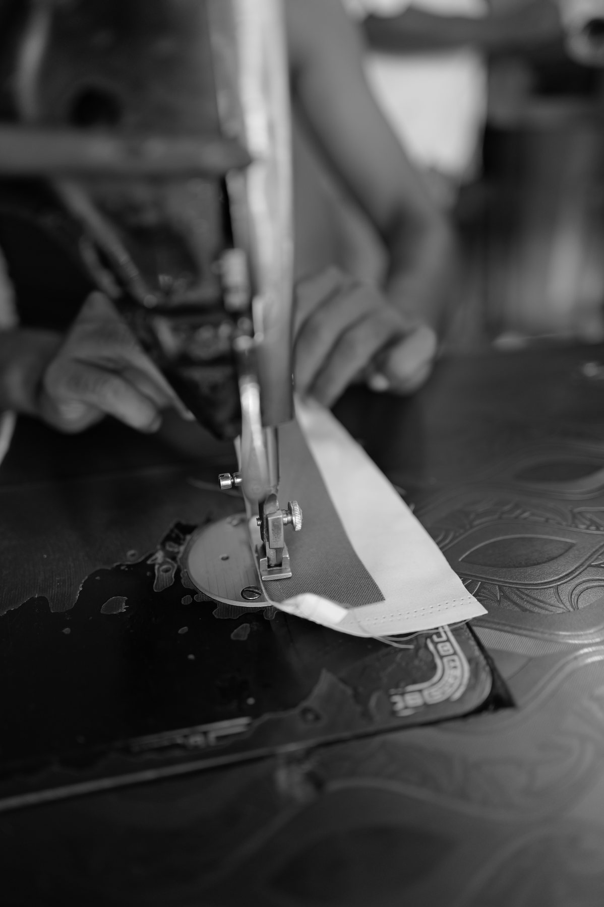 Close view of hands guiding white cloth under the needle of a sewing machine