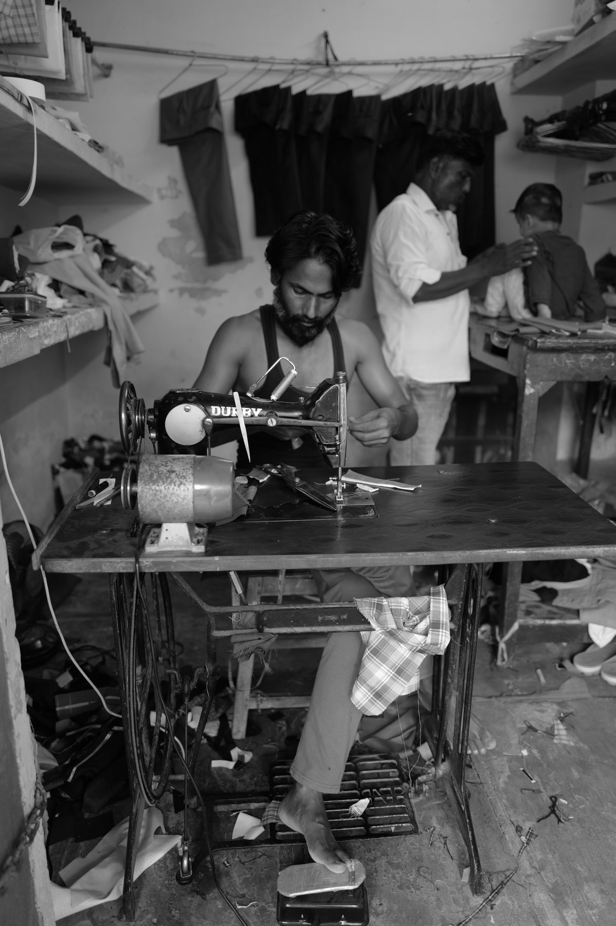 The tailor at his machine in the crowded workshop